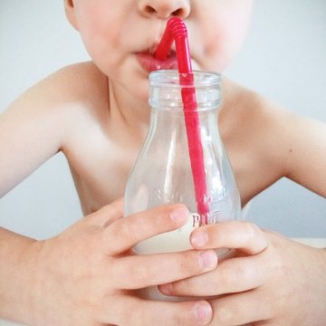 Boy drinking from milk bottle with a straw