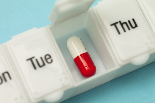 Close-up overhead view of a of a weekly pill box open on Wednesday with a pill inside