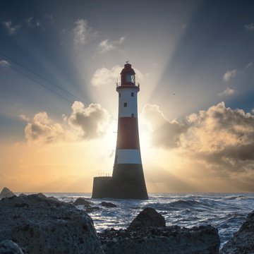 Beachy Head Lighthouse backlit by the rising sun, East Sussex, England, UK