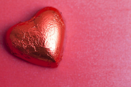 Close-up of a Heart Shaped Chocolate in red foil on a red background