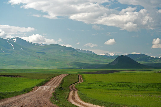 Dual lane dirt road leading towards hills