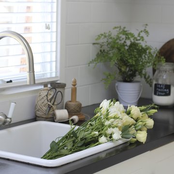 Close-up of a bunch of white roses, freesias and lisianthus flowers in a kitchen sink