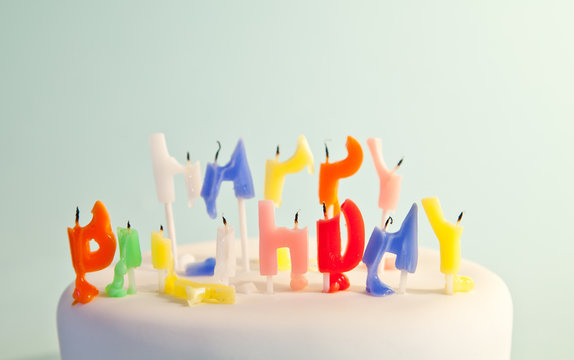 Close-up of a birthday cake with half burned happy birthday candles