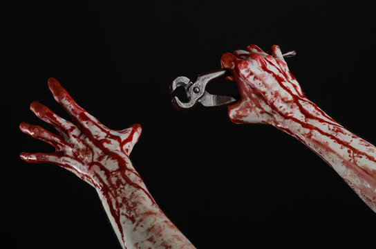 bloody hand holding a pliers on a black background