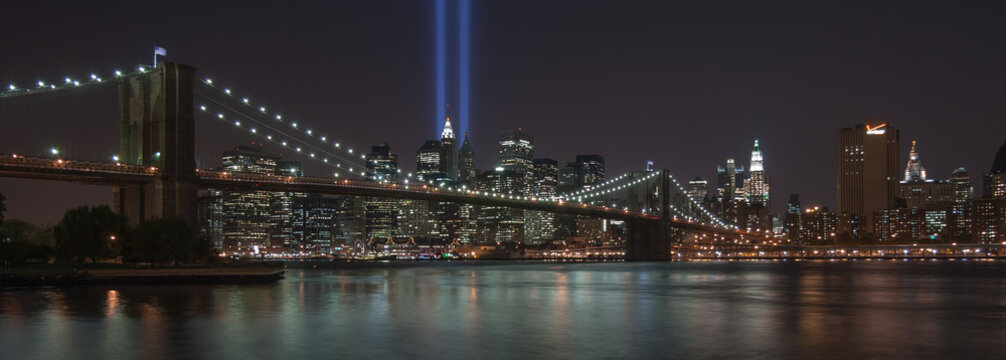 USA, New York, New York City, Illuminated skyline with Brooklyn Bridge blue rays of light