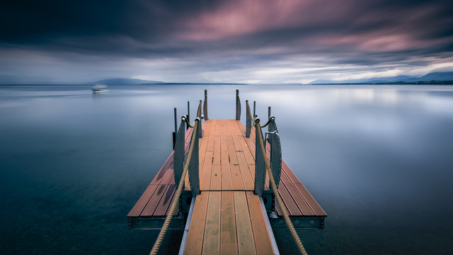 Wooden pier in a lake with a boat in the distance, Morges, Vaud, Switzerland