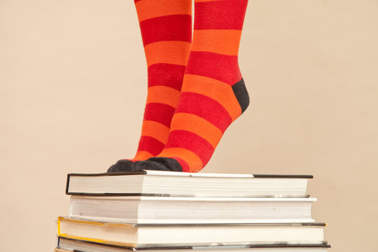 Feet in stripy socks, standing on pile of books