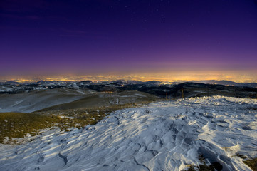 Snow sculpted by wind in a moonlit mountain scene at night.