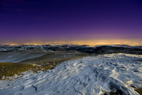 Snow sculpted by wind in a moonlit mountain scene at night.