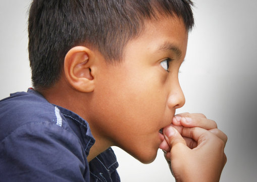 Close-up profile portrait of a boy biting his nails