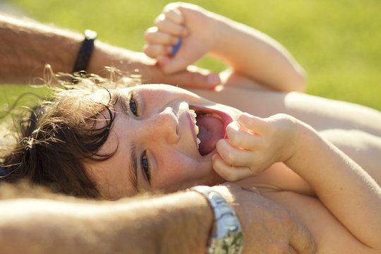 Close-up of a happy laughing Girl lying in a garden in summer being tickled