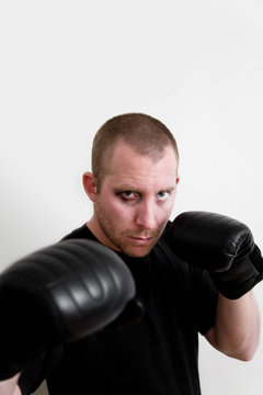 Portrait of a Male boxer in boxing gloves with a black eye standing in a fighting stance