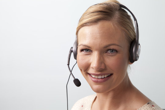 Smiling woman talking on the phone using a telephone headset