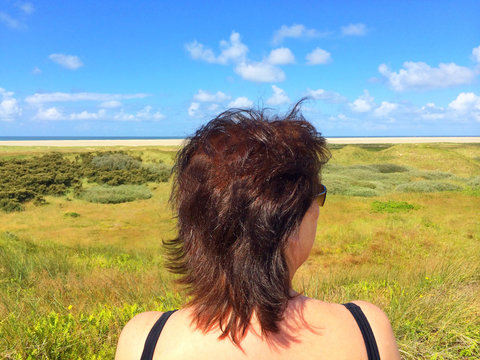 Rear view of woman sitting near the beach looking at summer view, Fanoe, Jutland, Denmark