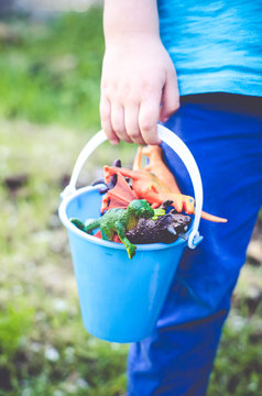 Boy holding bucket of dinosaurs