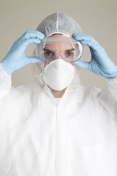 Close-Up portrait Of a scientist wearing a protective face mask, safety goggles, surgical gloves and a protective suit