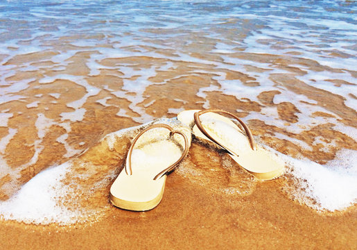 Flip flops on the beach in the ocean surf, Bang Kao, Phetchaburi, Thailand