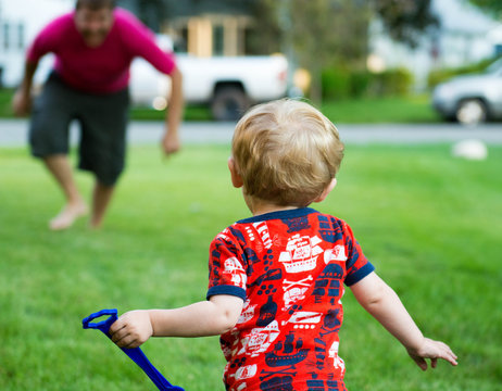 USA, Indiana, Little boy running to dad outside on a summer night