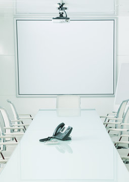 Empty Conference room in an office with a phone, overhead projector and blank screen