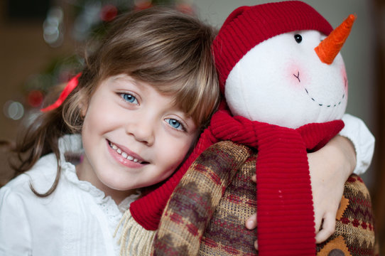 Portrait of a smiling girl cuddling a snowman today at christmas