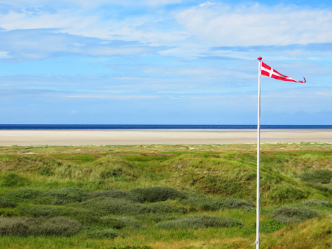 Sandy Beach and sea view with a traditional Danish pennant flag on a flagpole, Fanoe, Jutland,  Denmark