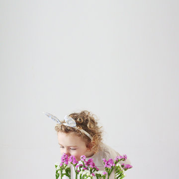 Girl smelling flowers against white background