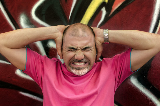 Man frowning and holding head in hands in anger