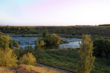 Obraz premium Forest River rapids at sunset.