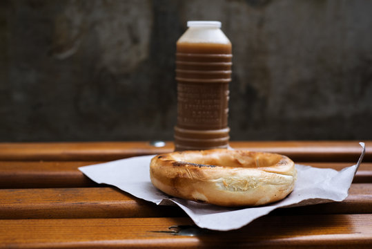 Close-up of a bottle of Boza (fermented malt drink) and bagel on a wooden table