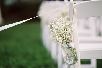 USA, Florida, Orange County, Winter Park, Close-up shot of bunch of baby's breath flowers in a mason jar and white ribbon attached to back of white chair