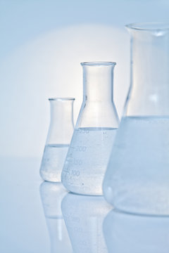 Close-up of a row of three conical glass flasks filled with clear liquid