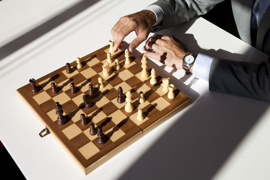 Overhead view of a Businessman in a suit sitting at a table playing chess