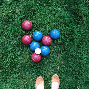 Bocce ball on green grass in park with woman's shoes