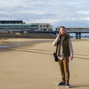 UK, Blackpool, Man with mobile phone on beach