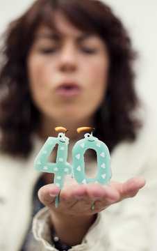 Close-up portrait of a brunette Woman blowing out 40th birthday candles in her hand 