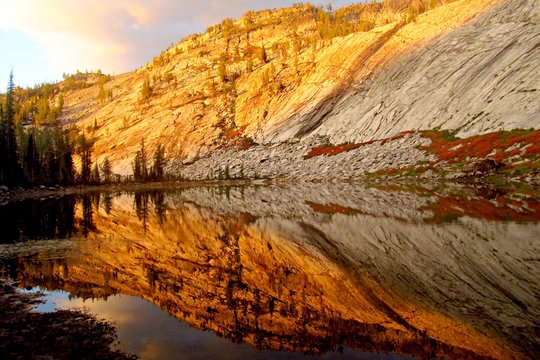 USA, Bitterroot Mountains, Morning light and rock reflecting in lake