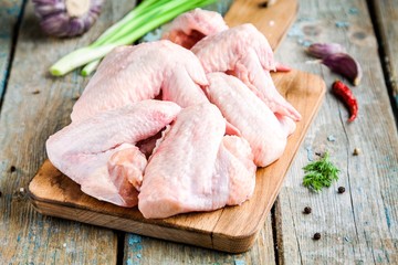 Fresh raw chicken wings with onion and peppers on cutting board