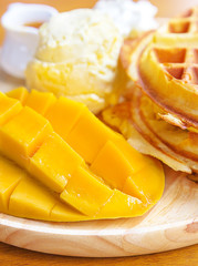 Mango with waffle and ice cream on wooden board