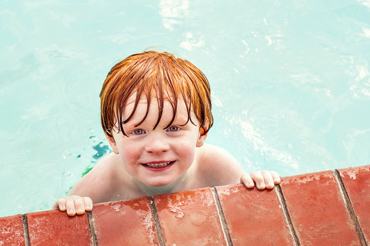 Overhead portrait of a smiling redhead boy in swimming pool