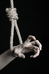 Fototapeta na wymiar human hand hanging on rope loop on a black background