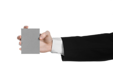 Man in black suit holding a gray blank card in hand isolated