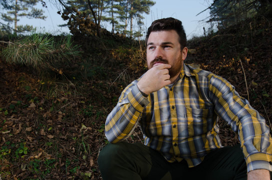 Thoughtful young man in casual clothing sitting in a forest, Sarajevo, Bosnia and Herzegovina