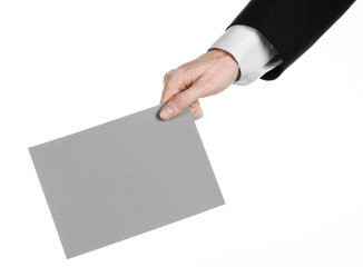 Man in black suit holding a gray blank card in hand isolated