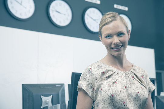 Businesswoman in office with computer terminals and world clocks in background
