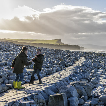 Two boys having a pretend sword fight with sticks on the beach