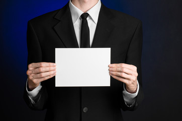 Man in black suit holding a white blank card in his hand