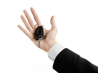 car salesman in a black suit holding a car key isolated
