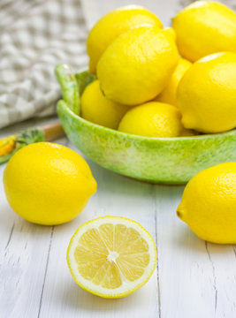 Lemons in a green bowl on wooden background