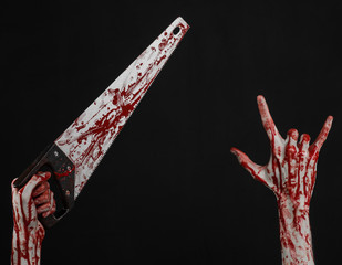 bloody hand holding a bloody saw on a black background