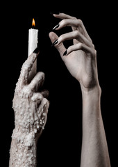 hands holding a candle, a candle is lit, black background